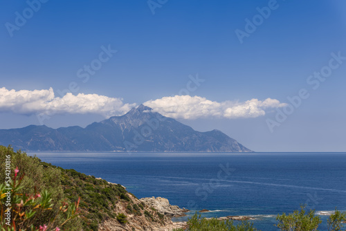 White cumulus clouds gathered together around the top of Mount Athos on a summer afternoon. Photo was taken from opposite coast of the Singitic Gulf of the Sithonia Peninsula  Greece