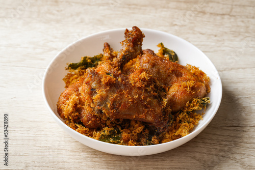 Ayam Goreng Padang. Traditional fried chicken with spice crumbs from Minangkabau, West Sumatra. served on white plate  photo