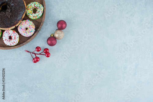 Tray of small donuts around a single, large donut on marble background