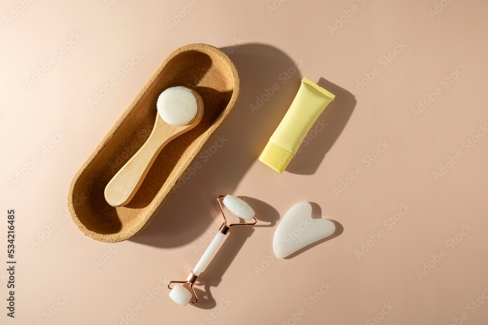 A face roller and quartz massager in the form of the heart, a face brush lying on the beige background A face roller and quartz massager in the form of the heart, a face brush lying on the beige background