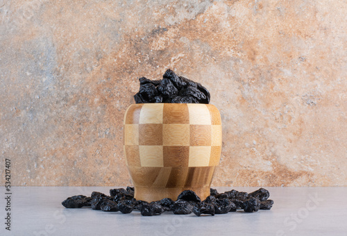 Black raisines in a wooden cup on concrete background photo