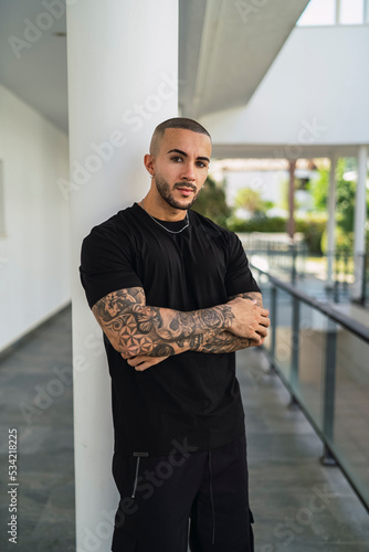 Obraz na płótnie Chico joven musculoso y tatruado posando con ropa urbana simple w salonie