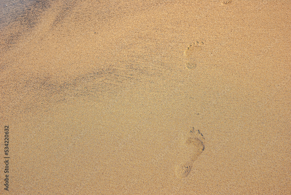 Human footprints walking along the coast. Clear traces of bare human feet on the sand. Human footprints walking along the coast. Clear traces of bare human feet on the sand.