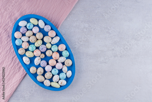 Colorful stone candies in a plate on concrete background