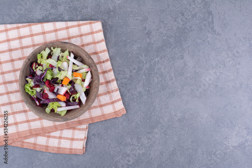 Dietic salad in a wooden plate with mixed ingredients