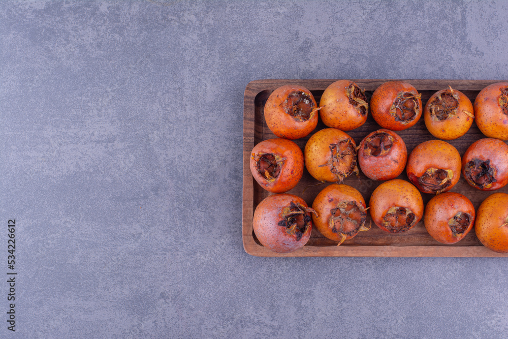 Medlars isolated in a wooden platter on the ground Medlars isolated in a wooden platter on the ground