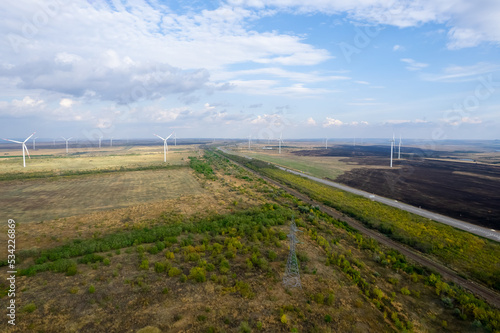 Panoramic shot from a bird's eye view of wind turbines in the middle of fields. Wind turbine construction in field blue sky with white clouds to generate renewable clean energy. concept idea eco energ
