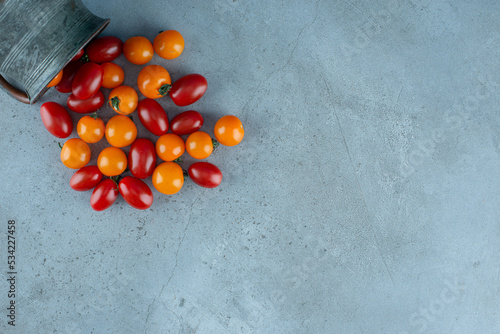 Red and yellow cherry tomatoes on grey background