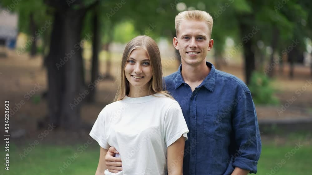 Beautiful young couple posing against the backdrop of the park. Go for a walk. Romantic date. Blondes. Happiness
