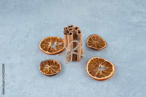 Cinnamon sticks and dry orange slices on blue background