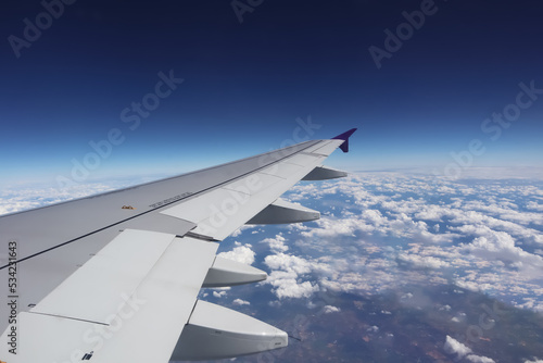 Aerial view from window of aircraft show aircraft wing and engine with horizon deep blue sky above all white clouds for transportation and travel airline business presentation background.