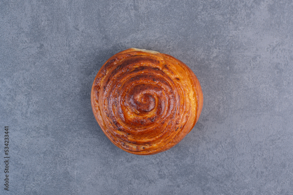 Fototapeta premium Single, crisp sweet bun displayed on marble background