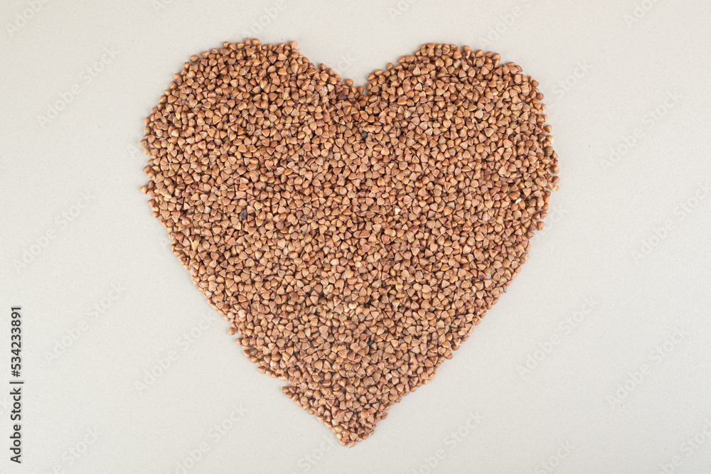 Buckwheat seeds in heart shape on concrete background Buckwheat seeds in heart shape on concrete background