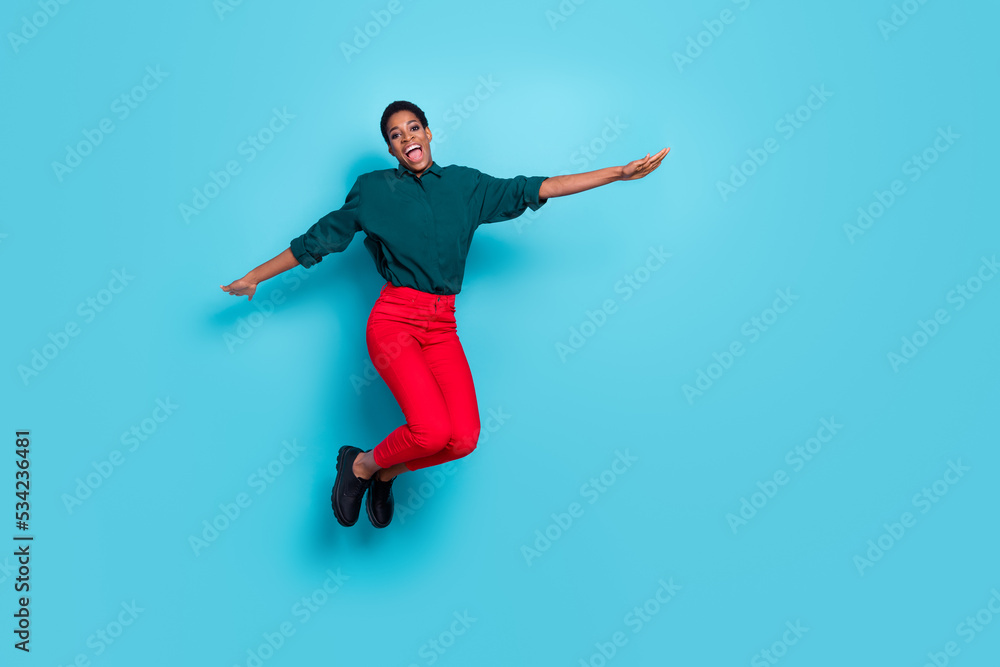 Photo of funky attractive androgynous human wear green shirt jumping high empty space isolated blue color background