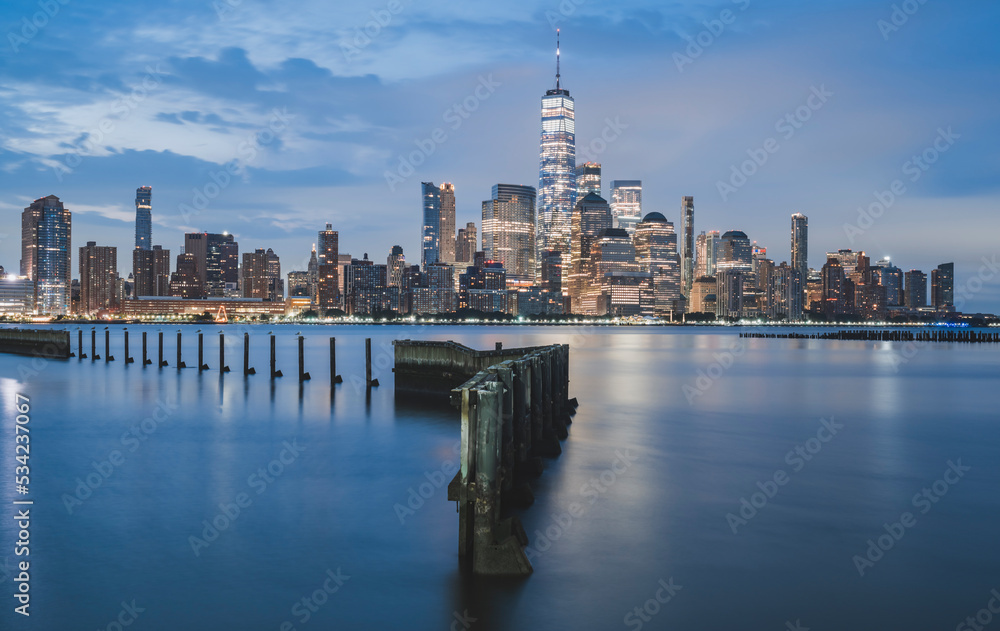 Fototapeta premium Panorama view of Manhattan skyline across the Hudson River from the waterfront Walkway in Jersey City at dusk