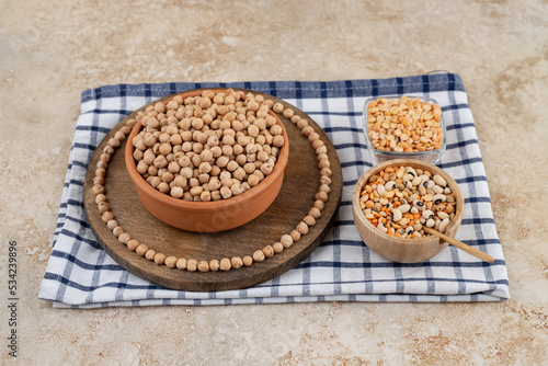 A wooden bowl full of unprepared peas with spices and beans photo