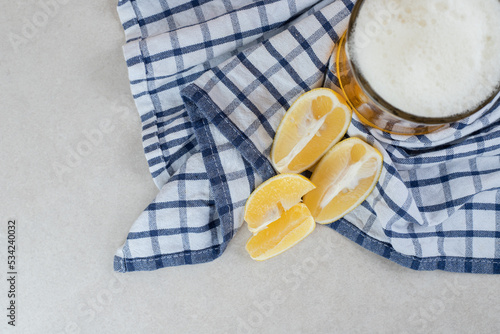 Glass of beer with lemon slices on tablecloth