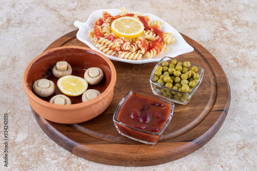 Appetizer ingredients with a platter of macaroni on marble background