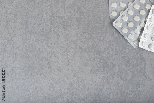 A lot of blisters with white pills on gray background