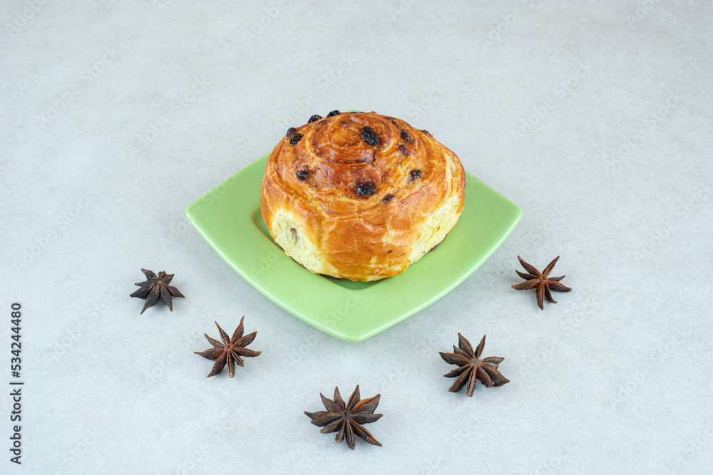 A green plate of sweet pastry and star anise on white background A green plate of sweet pastry and star anise on white background