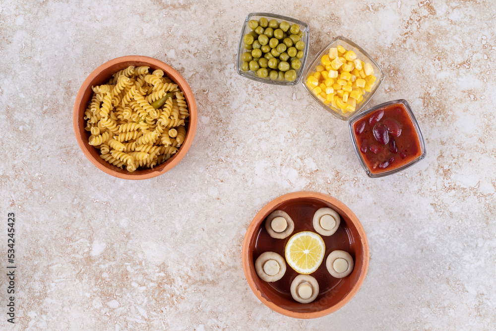 Wooden bowl of cooked paste and portions of various toppings on marble background Wooden bowl of cooked paste and portions of various toppings on marble background