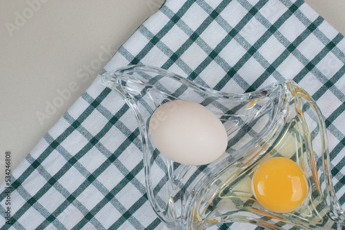 Fresh chicken white egg with yolk on glass plate photo