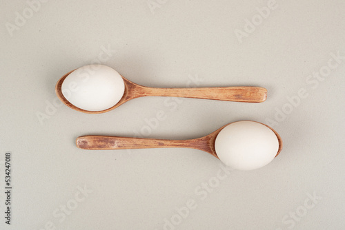 Two wooden spoons with chicken white eggs