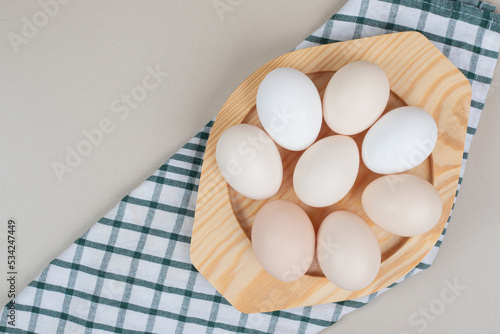 Several fresh chicken white eggs on wooden plate