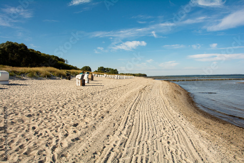 Fototapeta Naklejka Na Ścianę i Meble -  Sand Beach with wicker beach baskets  chairs  at the Baltic Sea with groynes in the sea