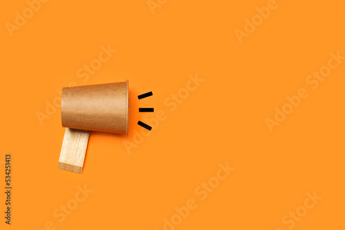 Imagen de concepto de negocio con megáfono de vaso de papel sobre un fondo naranja liso y aislado. Vista superior y de cerca. Copy space. Concepto:  Anuncio de concepto de atención. 