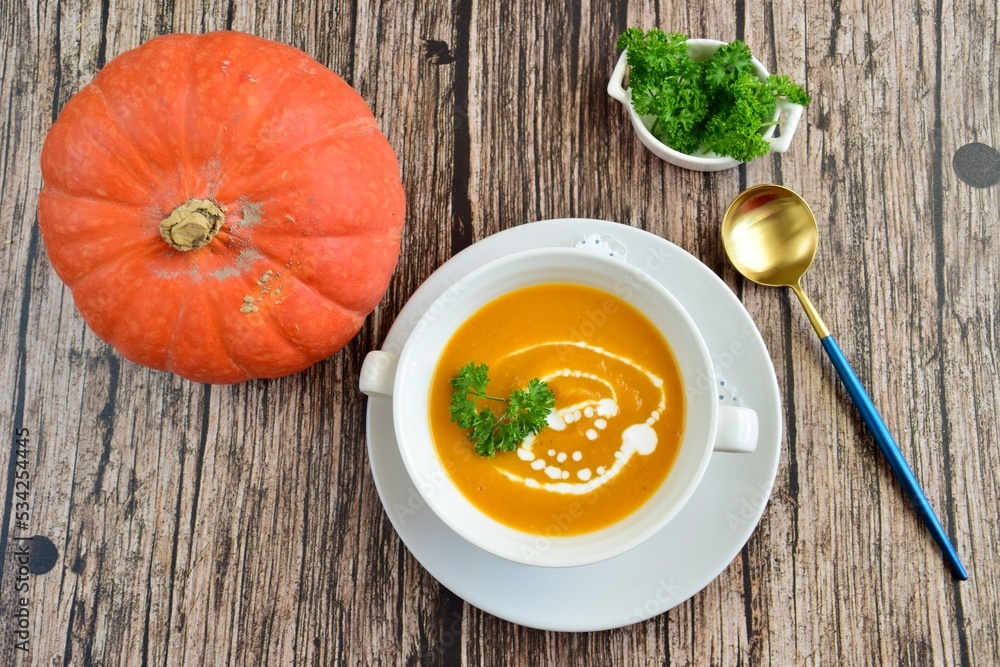 Pumpkin soup with coconut milk with parsley. Wooden background. Flat lay Pumpkin soup with coconut milk with parsley. Wooden background. Flat lay