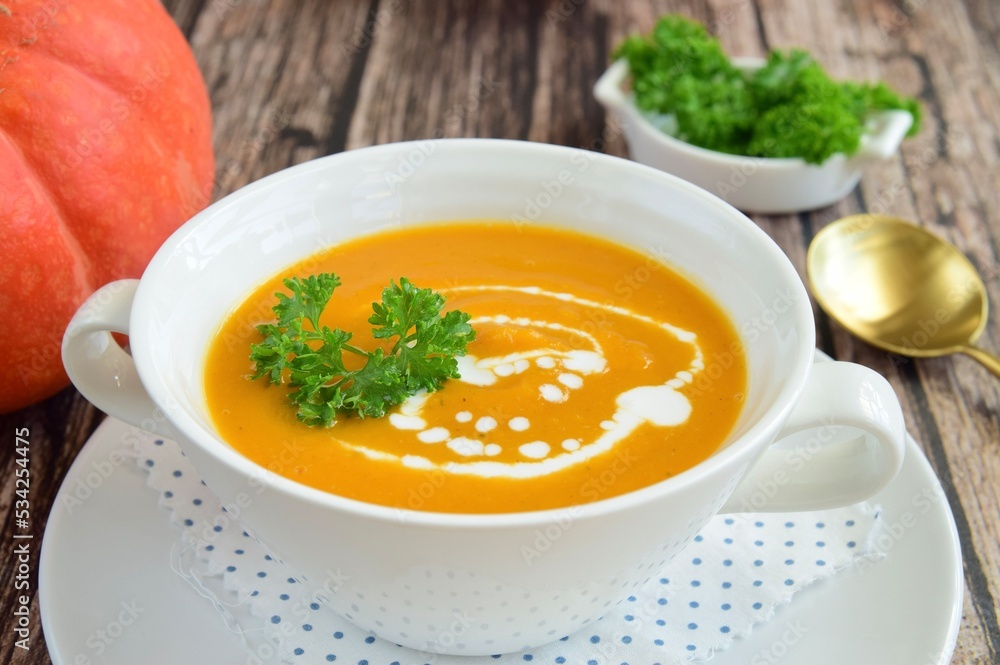 Pumpkin soup with coconut milk with parsley. Wooden background