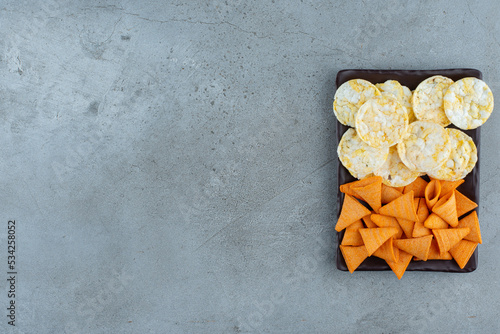 A dark plate full of crispy chips on gray background photo