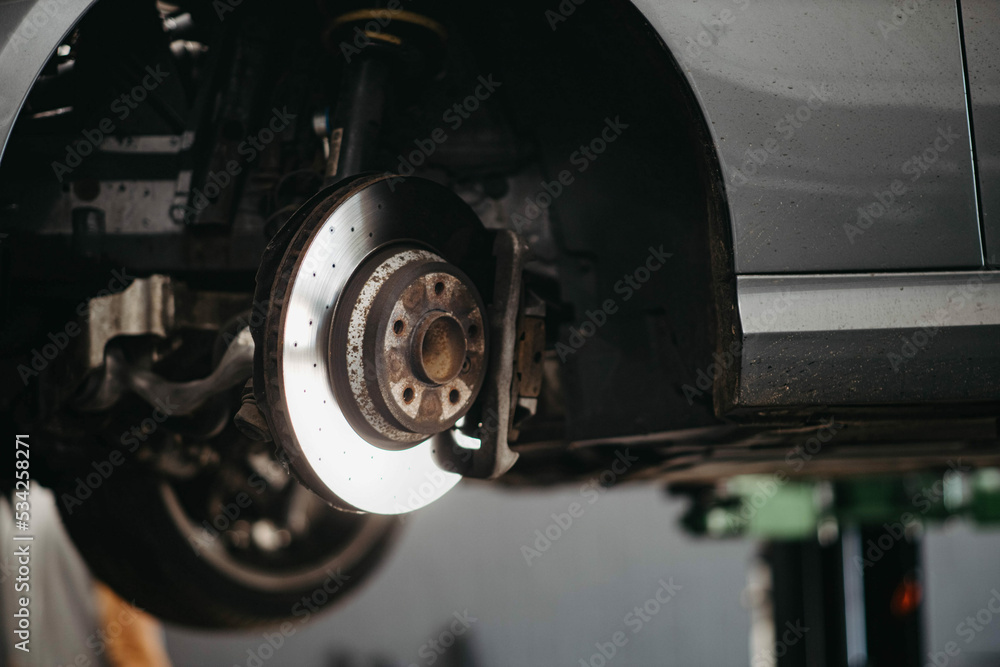 concept of replacing brake discs and pads, a car on a lift in a car service.