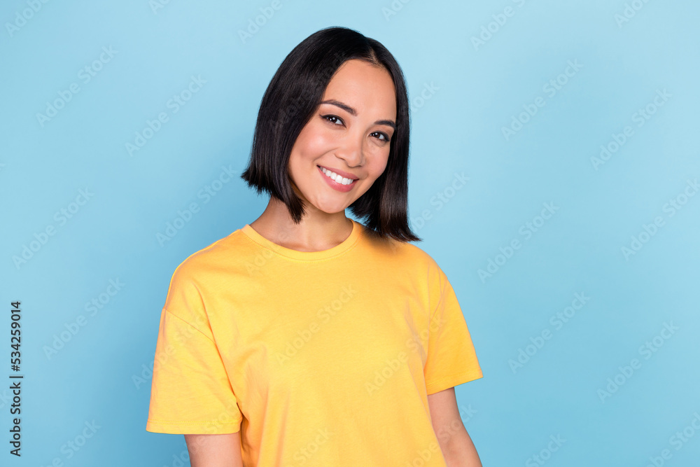 Portrait of nice positive gorgeous girl with bob hairstyle dressed yellow t-shirt smiling at camera isolated on blue color background Portrait of nice positive gorgeous girl with bob hairstyle dressed yellow t-shirt smiling at camera isolated on blue color background