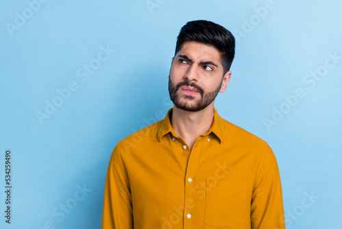 Photo of minded suspicious thoughtful intelligent person dressed yellow shirt look empty space isolated on blue color background © deagreez