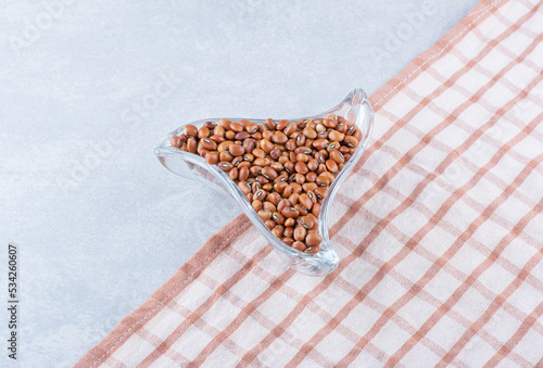 Small trinagular snack plate full of red beans on tablecloth, on marble background photo