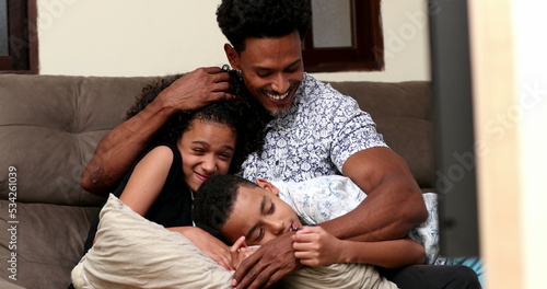 African father giving love and affection to son and daughter, candid at home