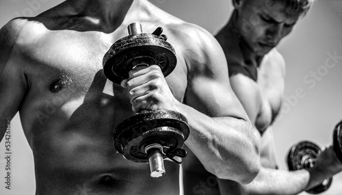 Dumbbell. Muscular bodybuilder guys, exercises with dumbbells. Black and white