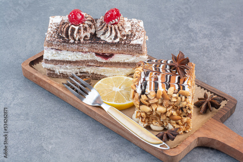 Two sweet delicious piece of cakes with star anise on wooden board