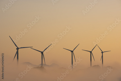 Wind turbines above the clouds at sunset photo