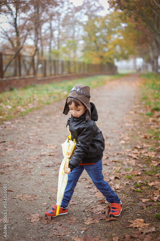 A six-year-old funny boy plays with a yellow umbrella in an autumn park. Children's fantasy concept A six-year-old funny boy plays with a yellow umbrella in an autumn park. Children's fantasy concept