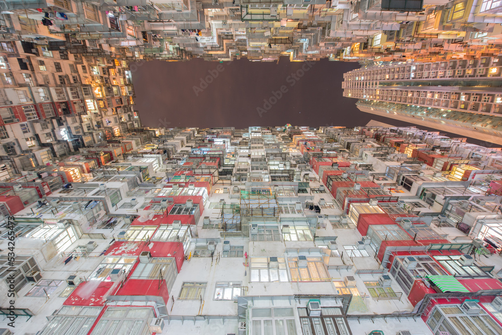 Low angle view of residential building in an old community with building lights on at night in Quarry Bay, Hong Kong. 