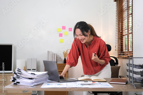 Beautiful Asian girl celebrate with laptop, success happy pose. E-commerce, university education, internet technology, or startup small business concept. Modern office or living room. photo