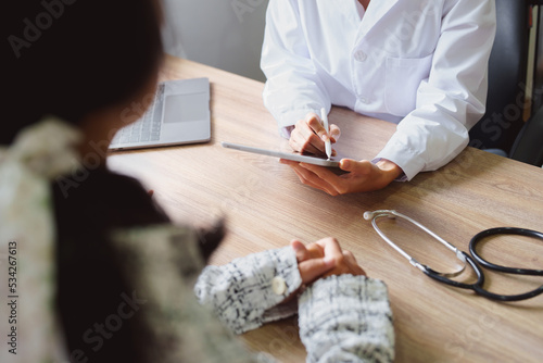фотографія Portrait of a doctor advising clients on health issues holding a tablet to work