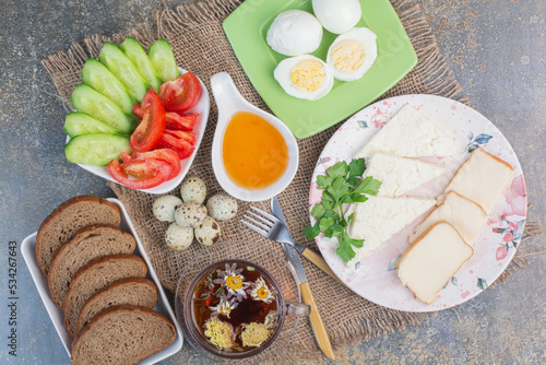 Breakfast table with vegetables, tea, bread, cheese and eggs