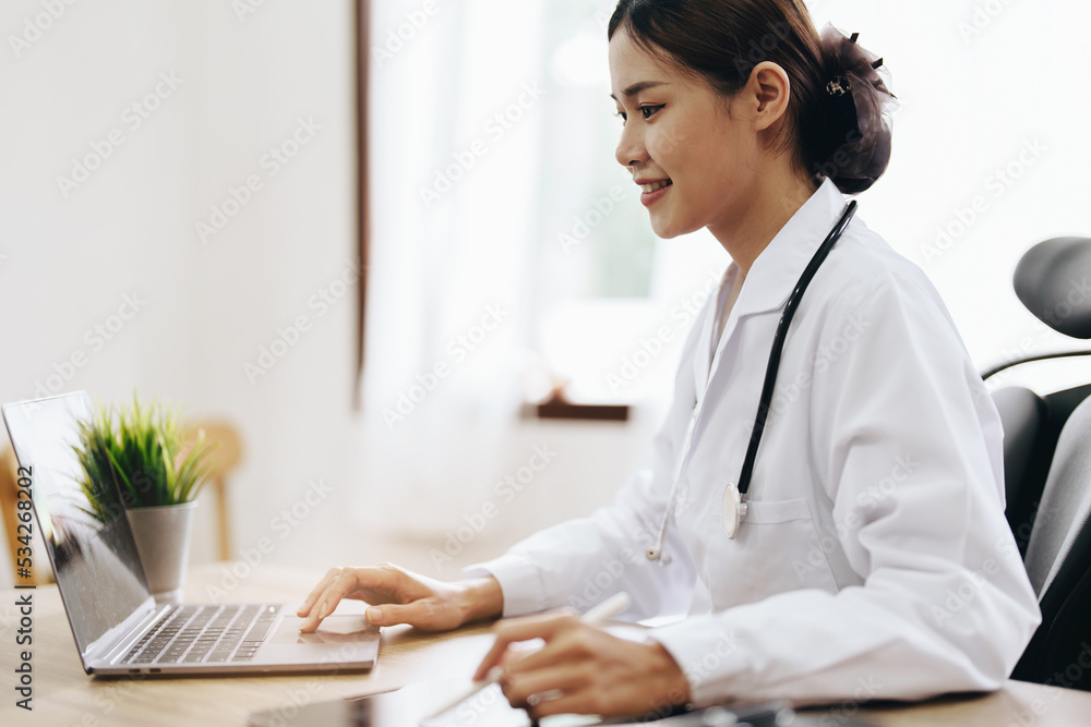 Portrait of an Asian female doctor using a computer and tablet to work Portrait of an Asian female doctor using a computer and tablet to work
