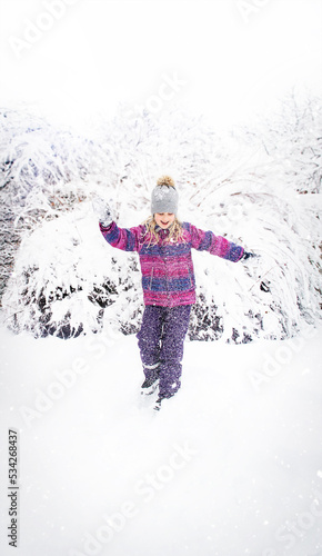 The child girl smiles and runs down the snowy hill.