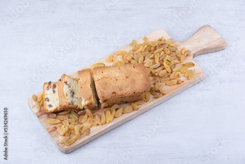Sweet loaf with bunch of raisins on wooden board