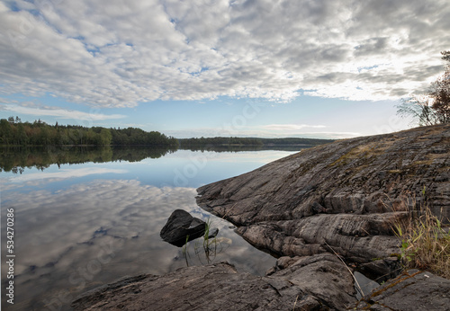 Lake with stony coast under cloudy sky landscape